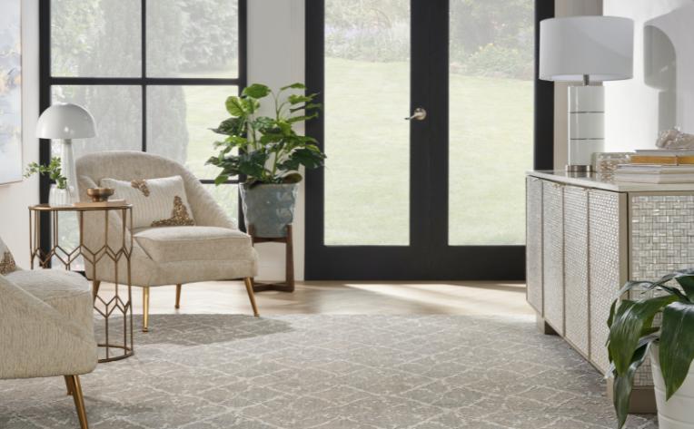 patterned grey carpet in living room with matching chairs and metal cabinet with mixed metal decor.